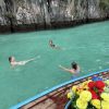 Girls swimming in crystal-clear water while island hopping in Thailand, surrounded by turquoise seas and limestone islands