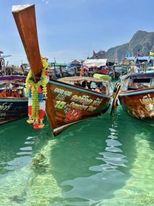 Island hopping in Thailand on a traditional long-tail boat, exploring turquoise waters, limestone cliffs, and hidden lagoons