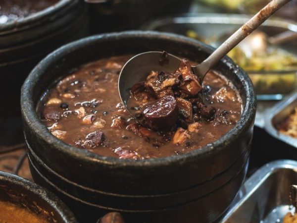 Traditional Brazilian feijoada dish served with rice, beans, orange slices, and farofa, part of a Brazil group travel experience in Rio de Janeiro.
