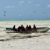 A group of Maasai sitting on a traditional wooden dhow boat in the turquoise lagoon of Paje Beach, Zanzibar.