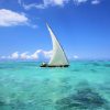 Traditional wooden dhow boat sailing on crystal-clear turquoise waters in Zanzibar during a Gagago island tour.