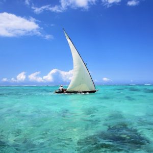 Traditional wooden dhow boat sailing on crystal-clear turquoise waters in Zanzibar during a Gagago island tour.