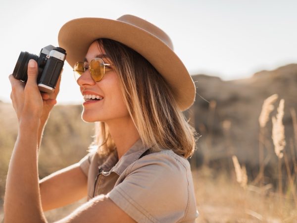 A woman holding a professional camera, taking a photo of wildlife from an open-top Gagago safari vehicle in Africa.