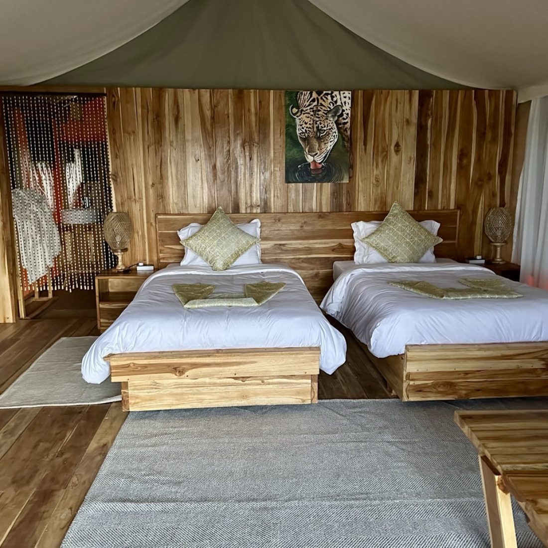 Interior of a luxury tented camp room in the Serengeti featuring two twin beds with premium linens and safari-style decor.